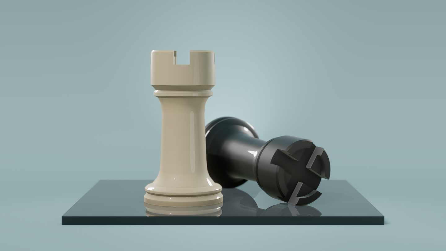 Two lacquered chess rooks, one standing and one fallen, on polished slate